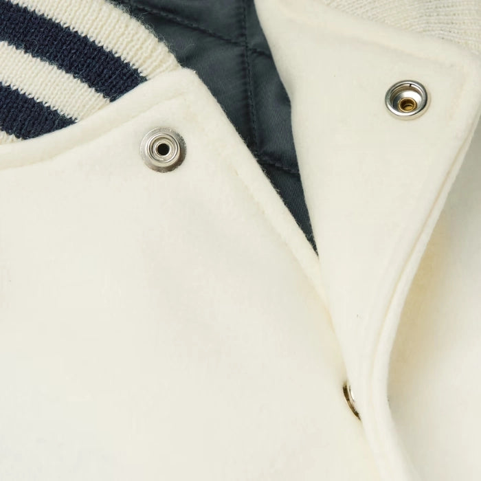 Close-up of a white varsity jacket with buttons and a navy stripe