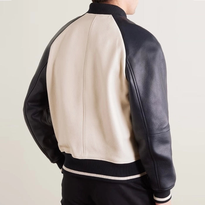 Back view of beige varsity jacket with black leather sleeves and ribbed hem.