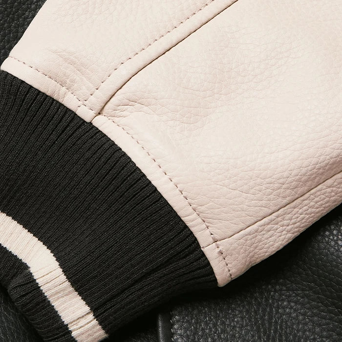 Detailed view of ribbed cuff and cream leather sleeve of varsity jacket.