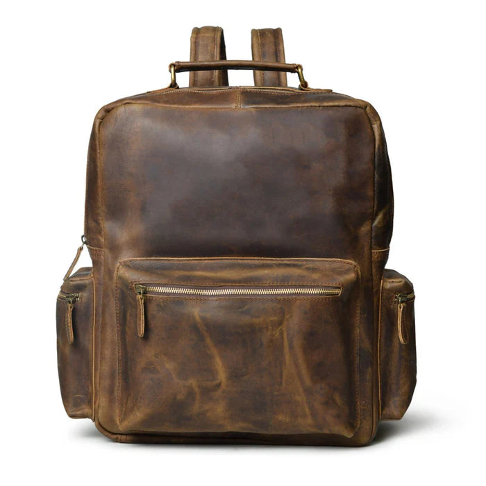 A vintage brown, full-grain buffalo leather backpack with adjustable shoulder straps, front pocket, and side zipper pockets.